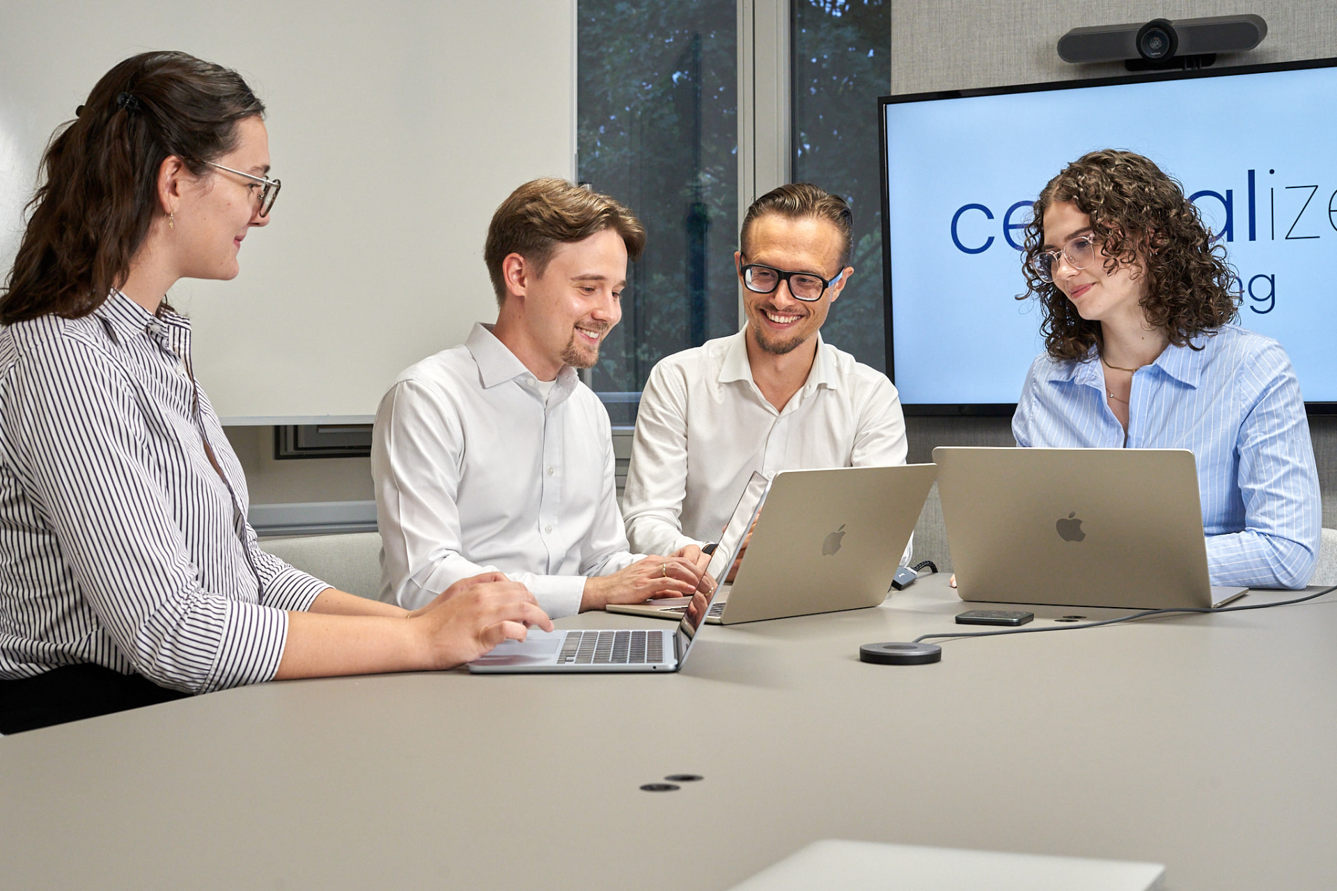 Das Centralize-Team sitzt gemeinsam an einem Konferenztisch und arbeitet an den Laptops